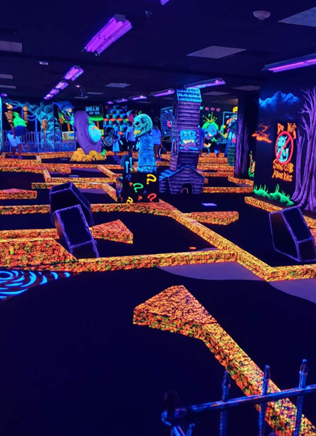 Parcours de mini-golf intérieur rétro éclairé en lumière noire, décor fluorescent