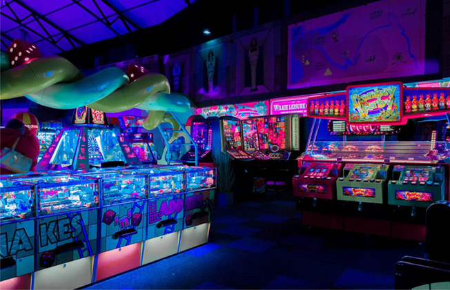 Salle d’arcades rétro avec machines lumineuses et ambiance néon dans un centre d’amusement